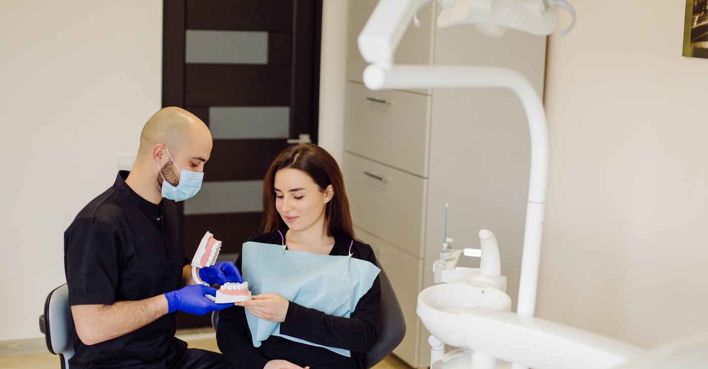 The dentist explains the implant procedure to the patient with a dental model