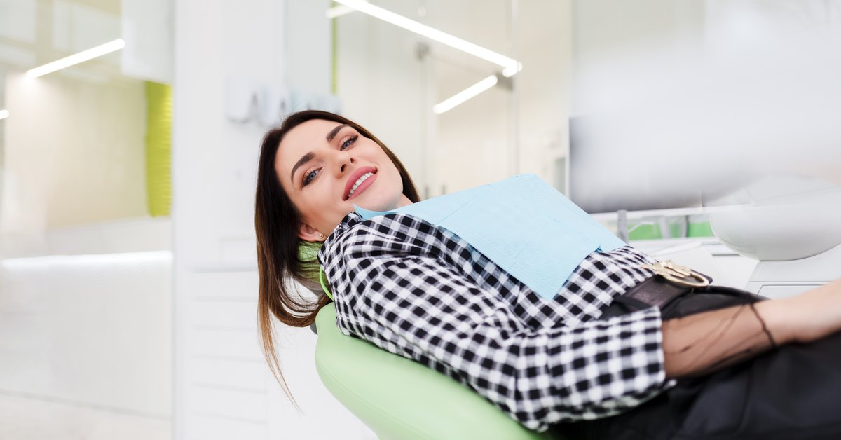 ¿Duele ponerse un implante dental? Paciente sonriendo y relajada en el sillón de la clínica antes de la intervención
