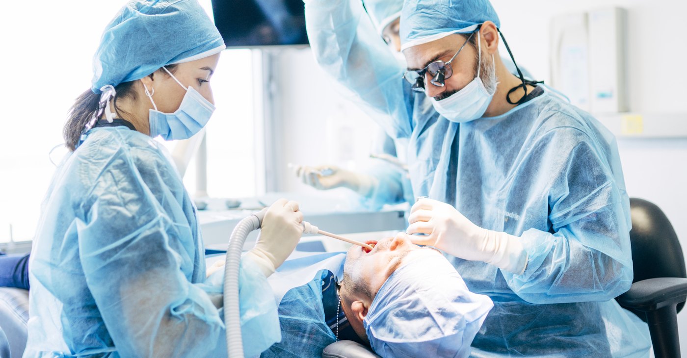 Equipo de la clínica colocando un implante dental en el sillón de cirugía