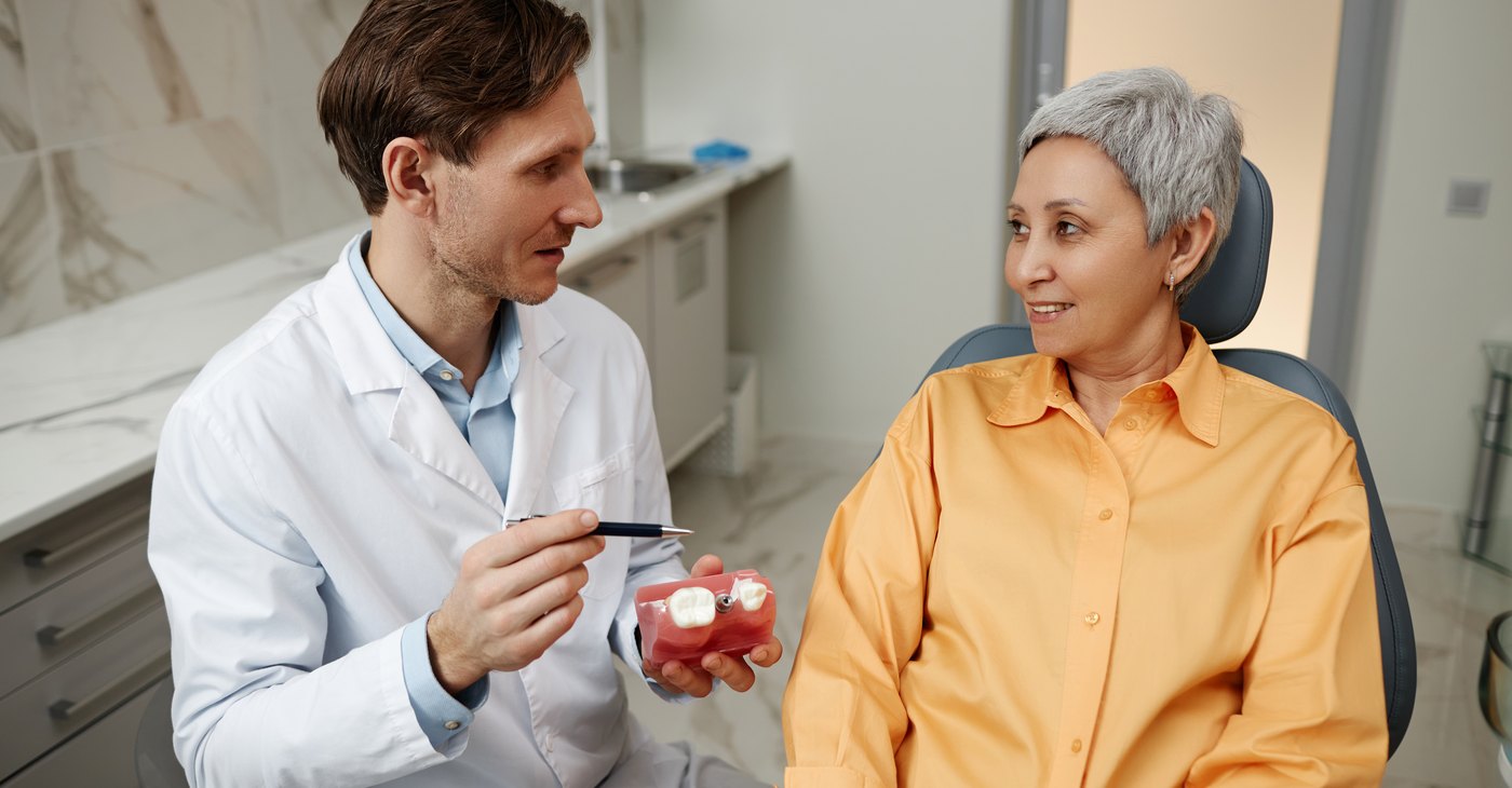 El dentista explica a la paciente las opciones con un modelo dental en la mano