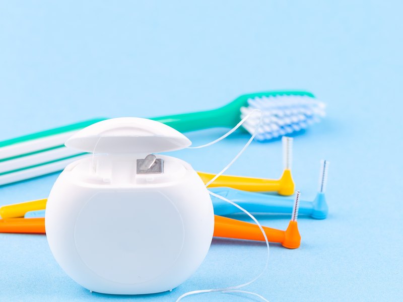 Hilo dental, cepillo de dientes y cepillos interproximales sobre fondo azul