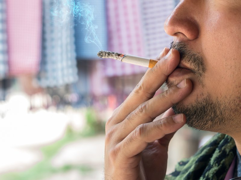 Primer plano de un hombre con barba fumando un cigarrillo
